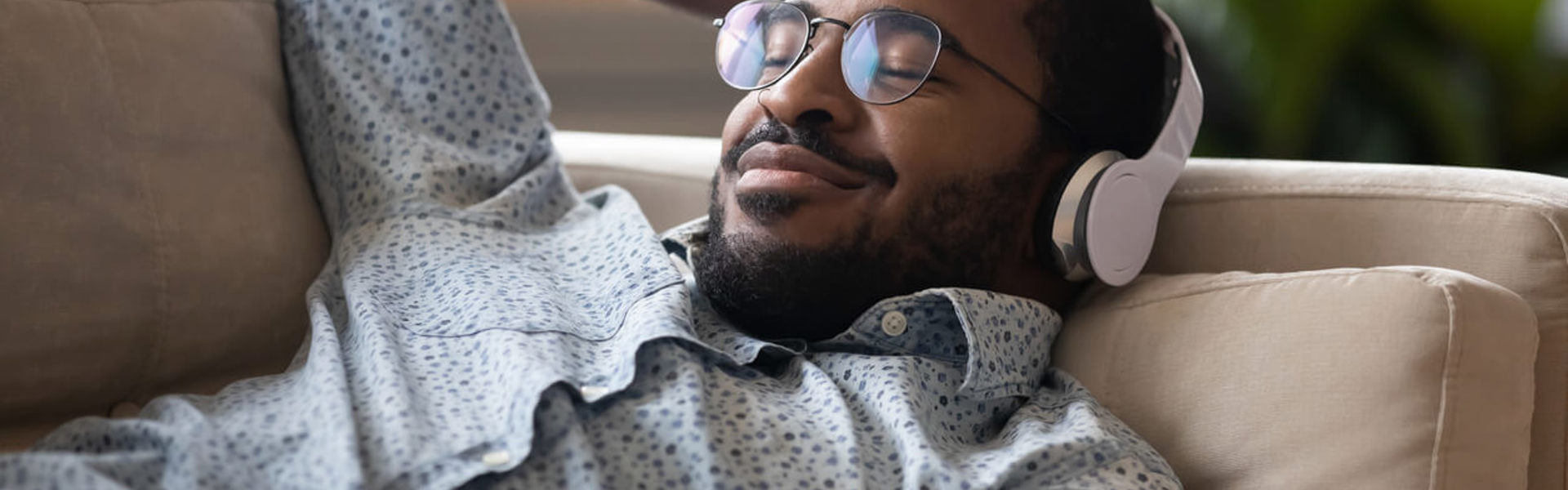 A man relaxing on a sofa with headphones on 