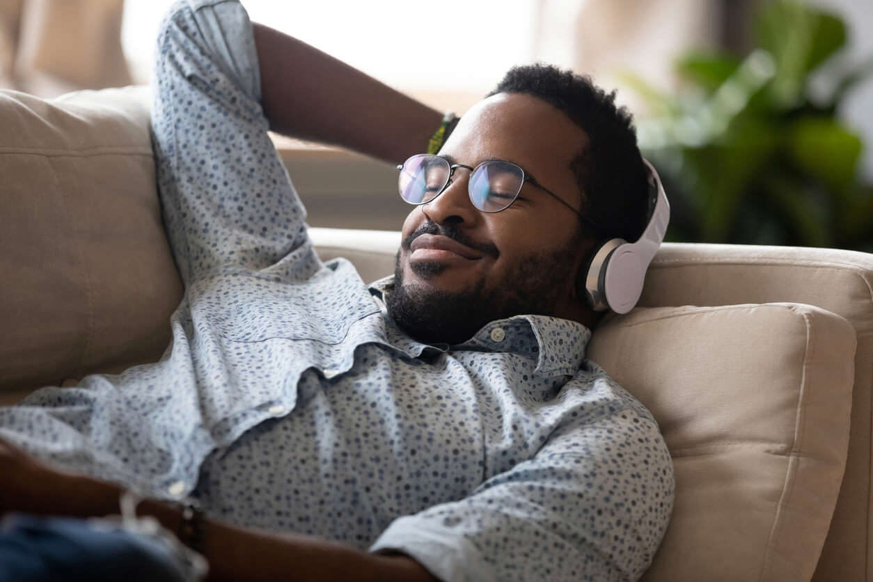 A man relaxing on a sofa with headphones on 