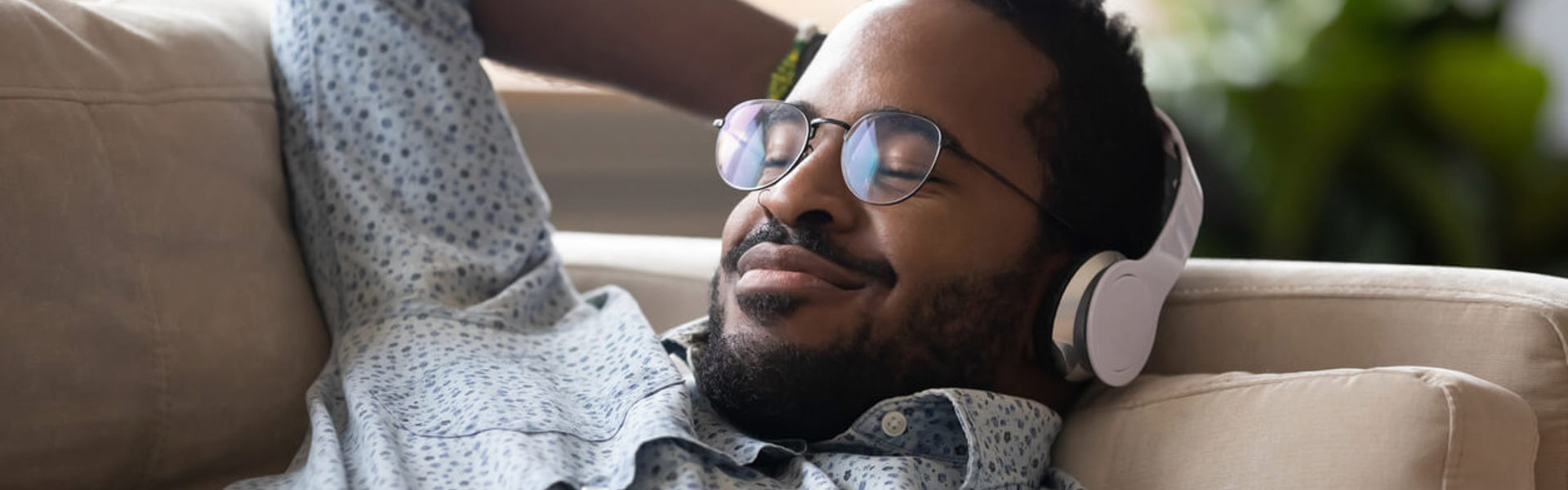A man relaxing on a sofa with headphones on