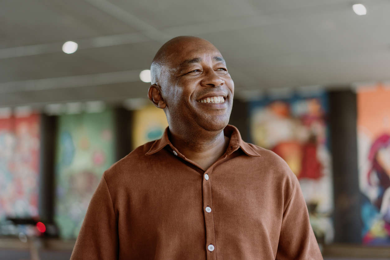 a man wearing a brown short sleeve shirt smiling