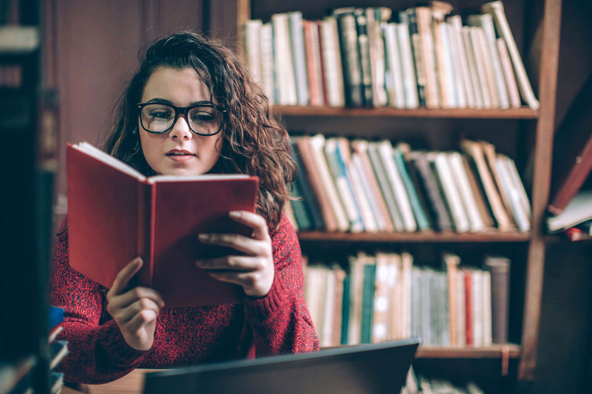 A woman reading a book in a library