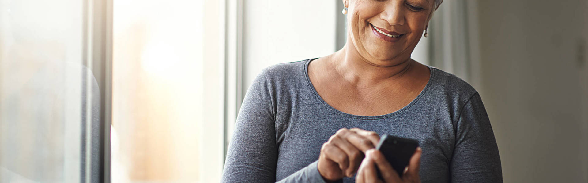 an older woman looking texting on her phone and smiling