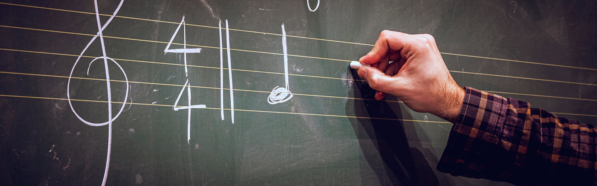 A man writing a musical score on a blackboard