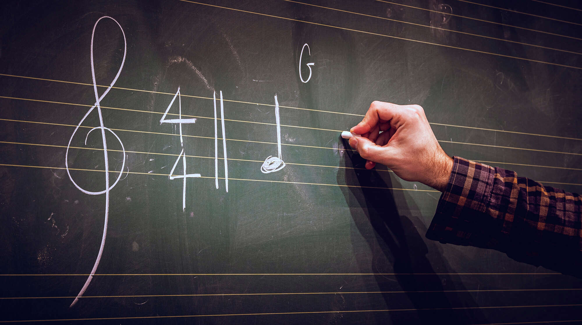 A man writing a musical score on a blackboard