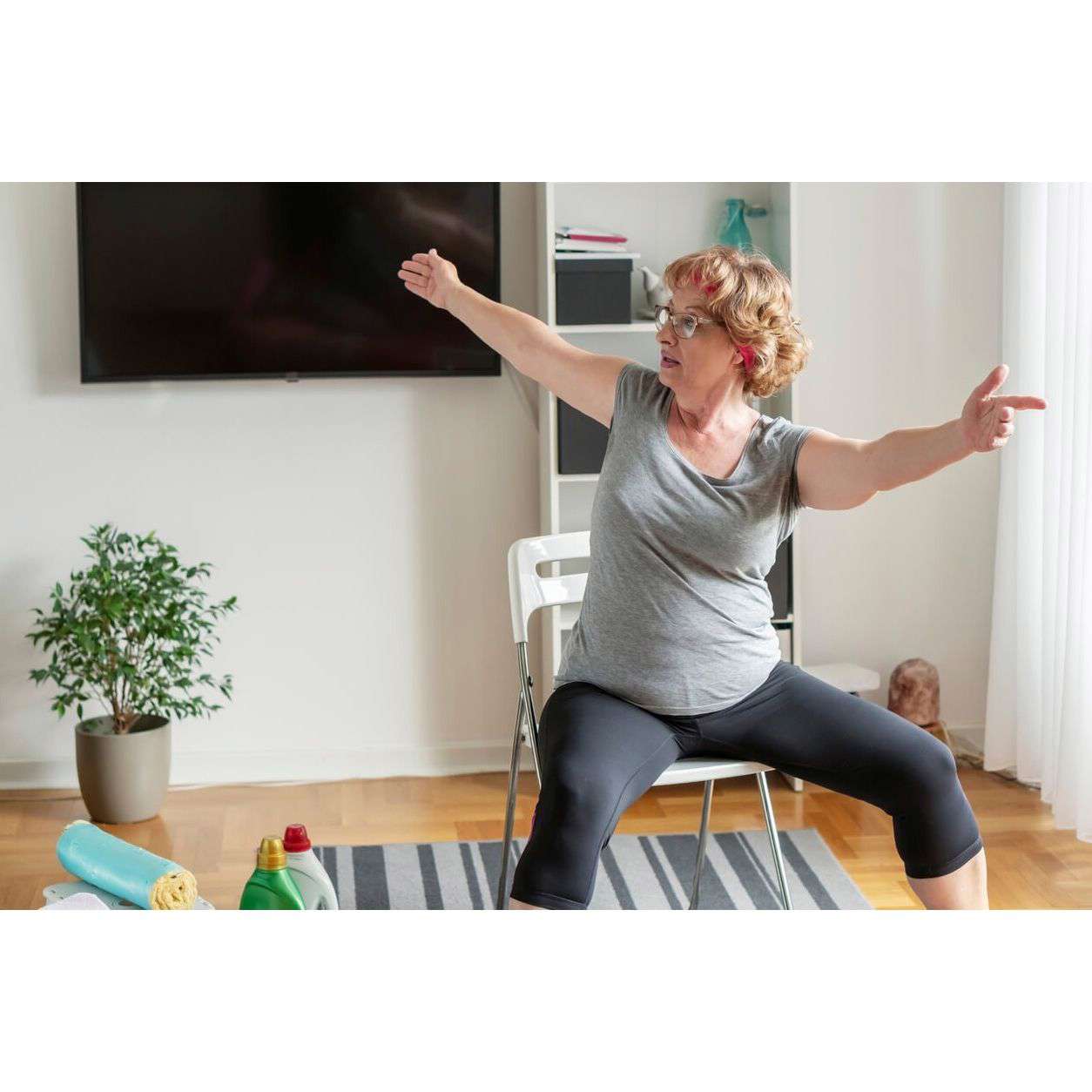 Woman sitting in her living room doing chair yoga stretches