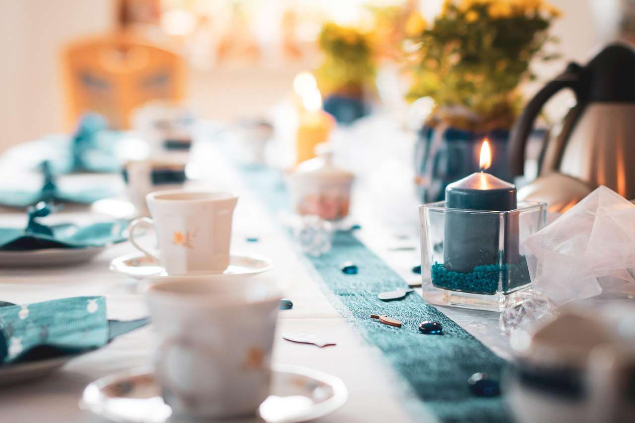 Main image: a dinner party table, with tea cups, candles and a DIY hand printed table runner, in teal and white colours.