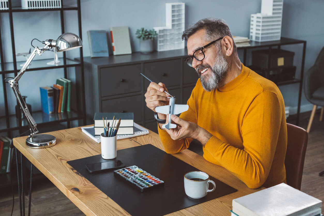 Mature man at office making plane model for next project.