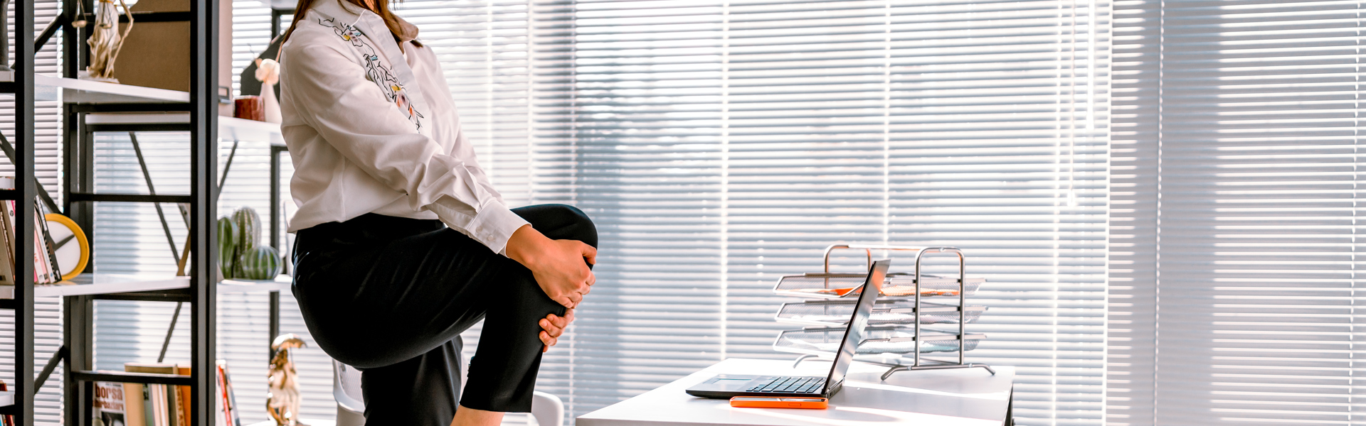 A woman standing and stretching her hamstring at a work desk whilst working