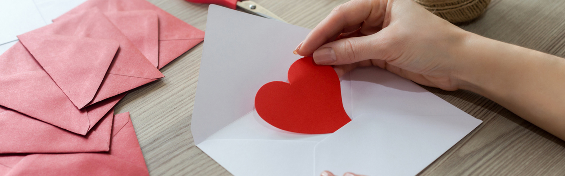 a person crafting with red and pink Valentine's paper hearts