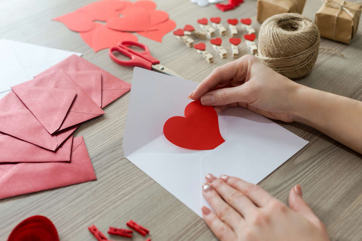 a person crafting with red and pink Valentine's paper hearts