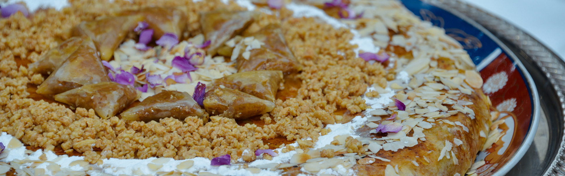 A fish pastilla topped with flaked almonds and edible flowers on a plate