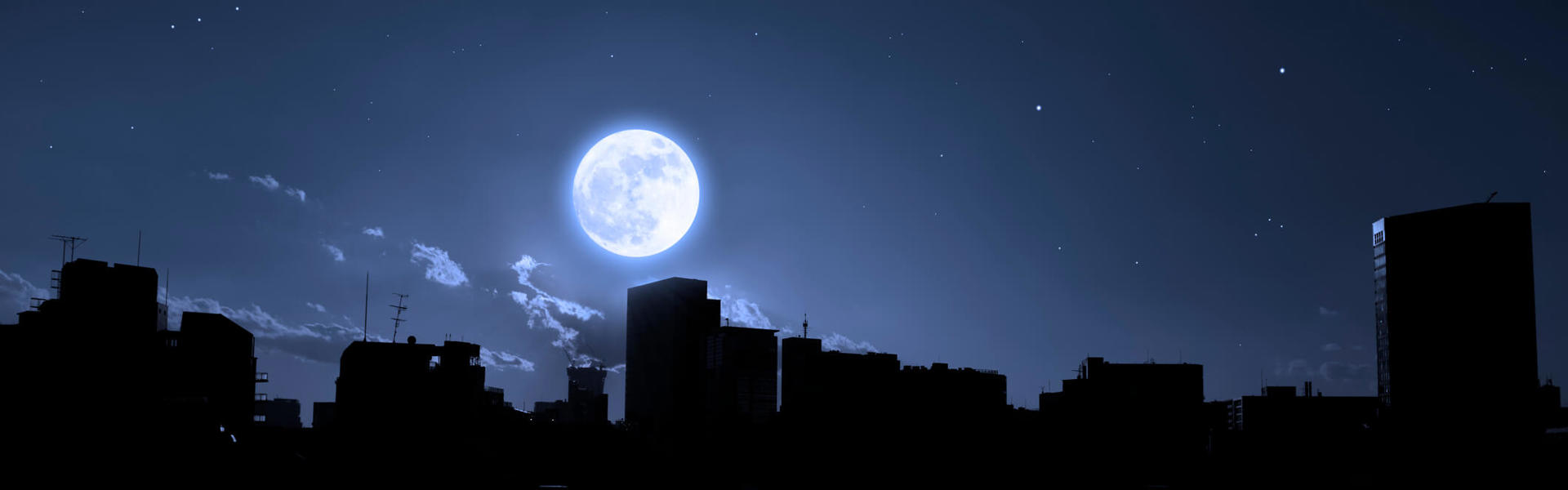 a full moon at night over a city skyline