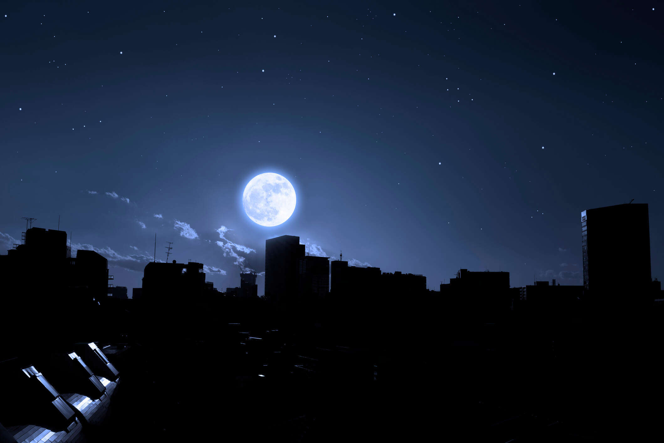 a full moon at night over a city skyline