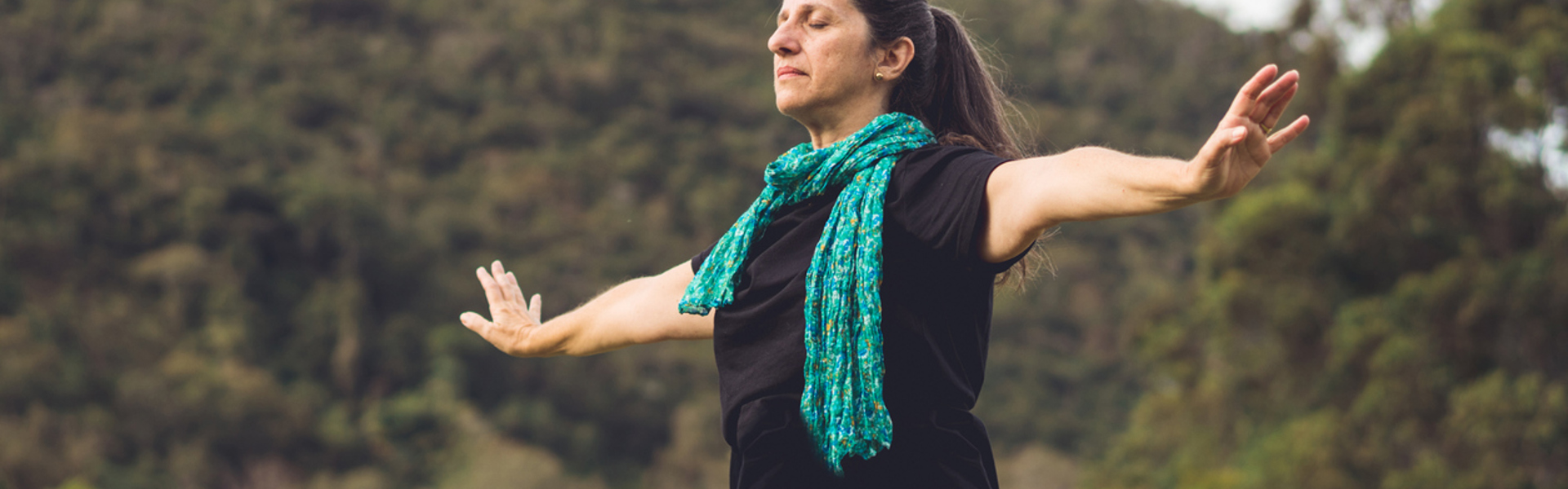 a woman wearing a blue scarf doing Qi Gong in nature