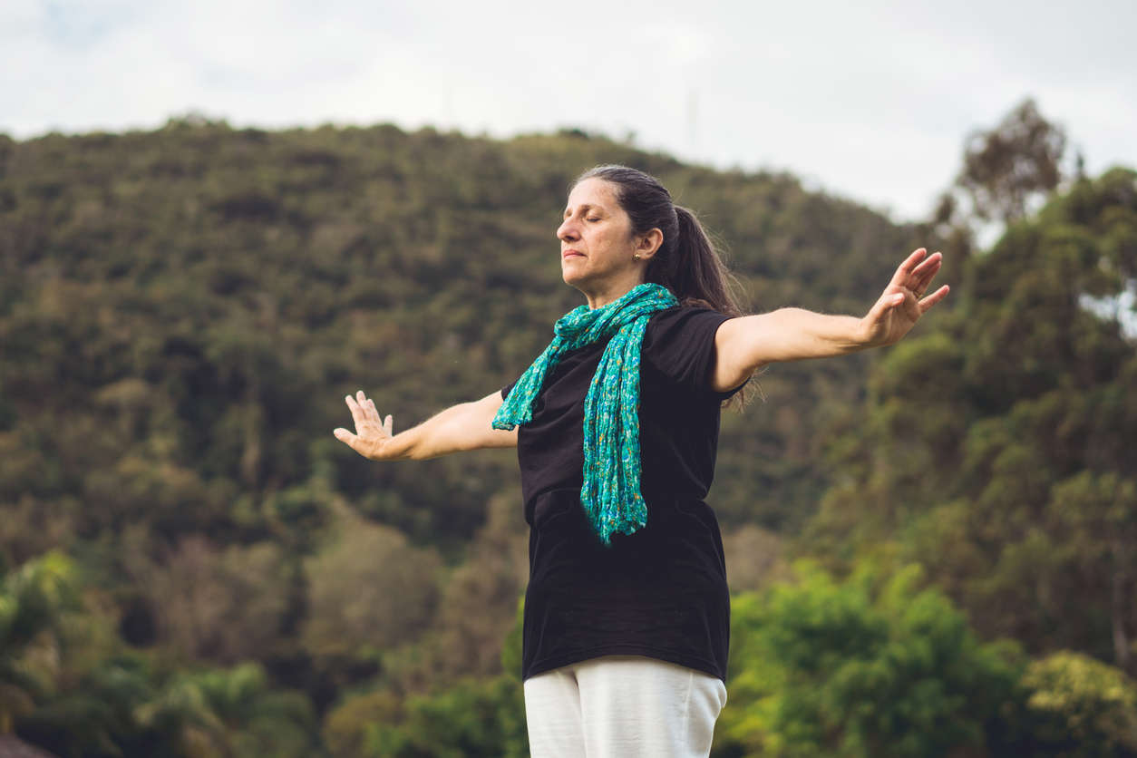 a woman wearing a blue scarf doing Qi Gong in nature