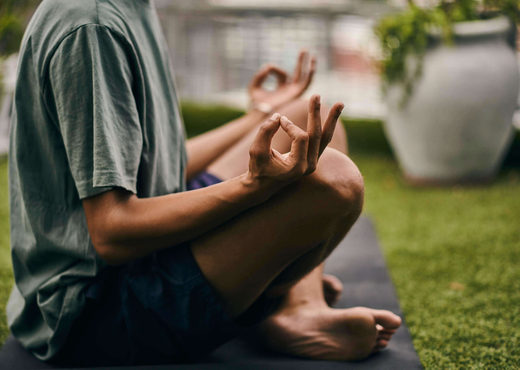Man sitting in the lotus position, meditating in his garden.
