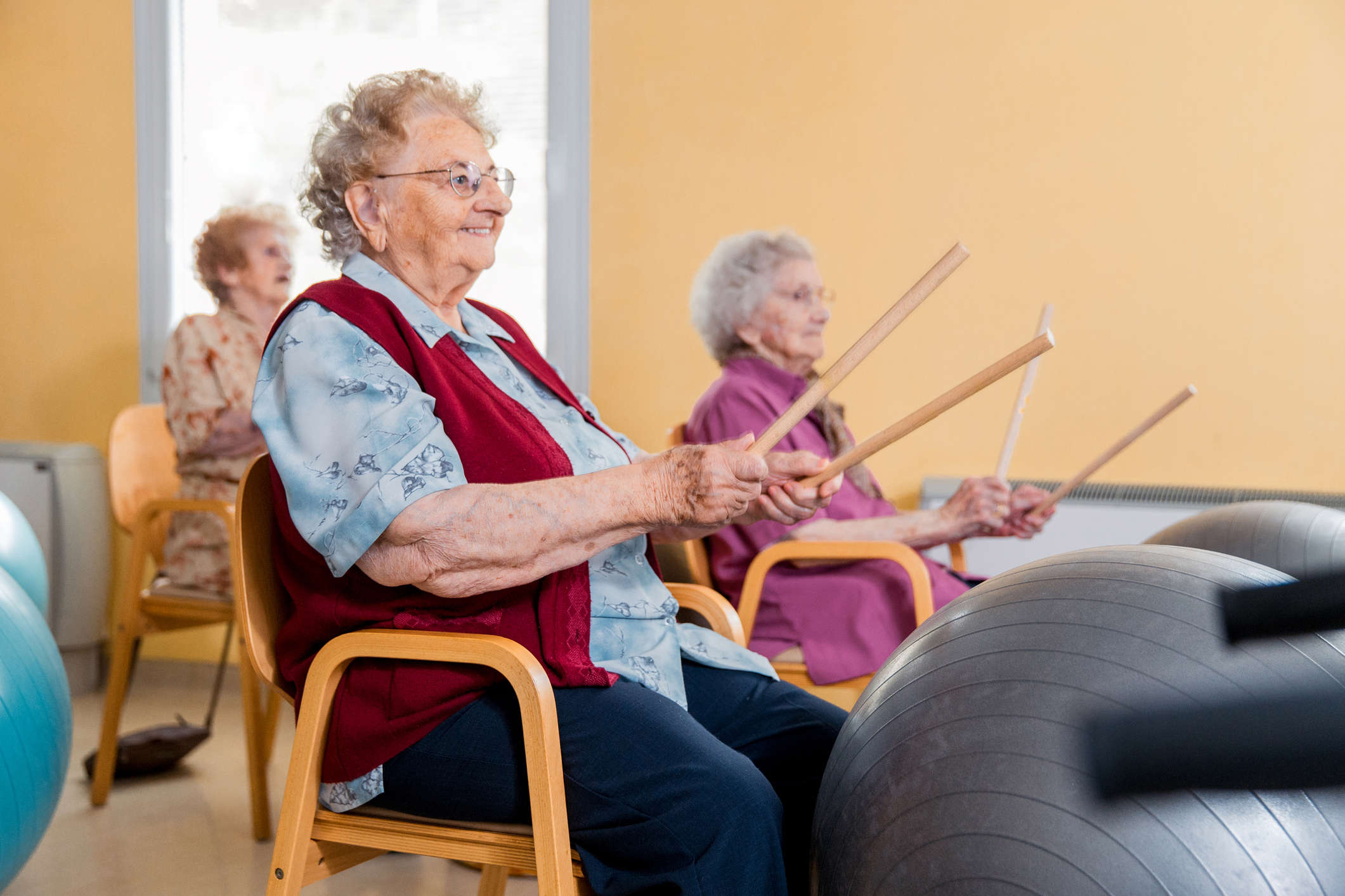 Older women having fun using Yoga Balls and Drumsticks as part of a Parkinson's Beats - Exercise Drumming class