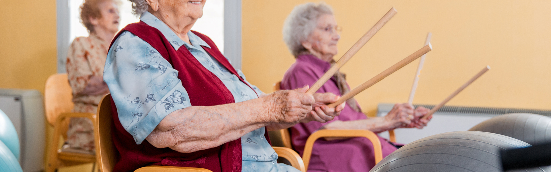 Older women having fun using Yoga Balls and Drumsticks as part of a Parkinson's Beats - Exercise Drumming class