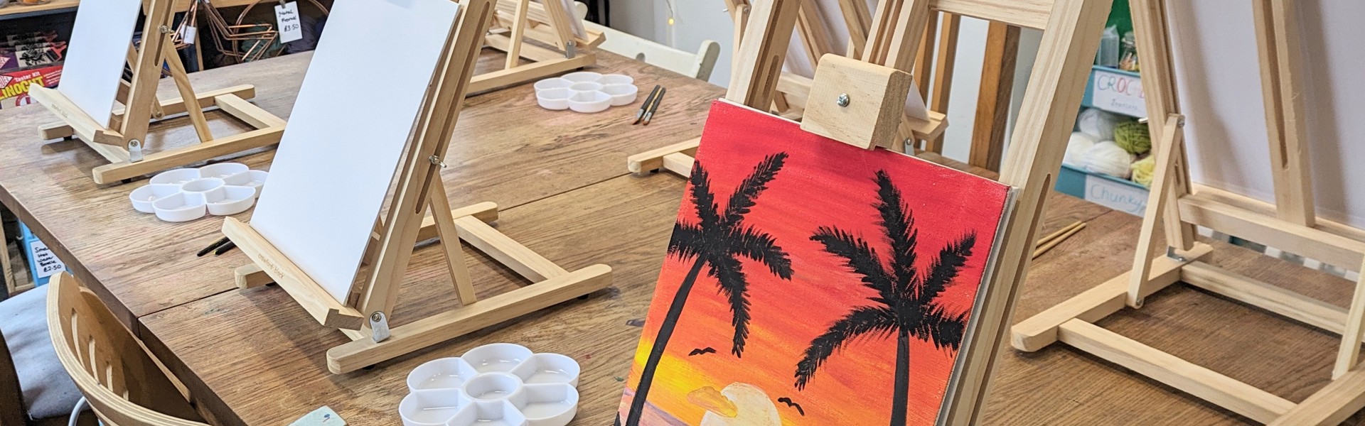 a hand painted tropical scene on a canvas resting on a easel 