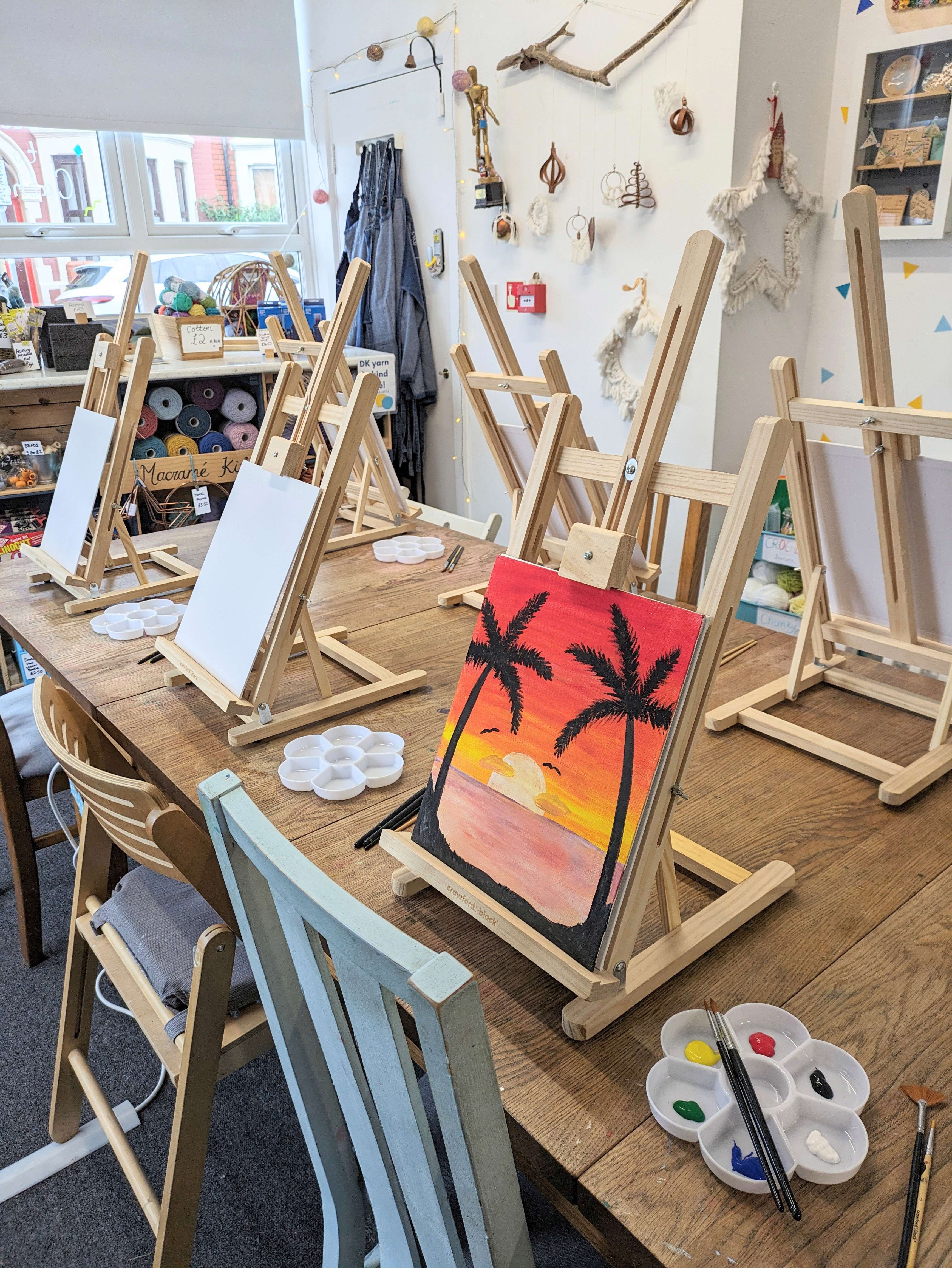 a hand painted tropical scene on a canvas resting on a easel 