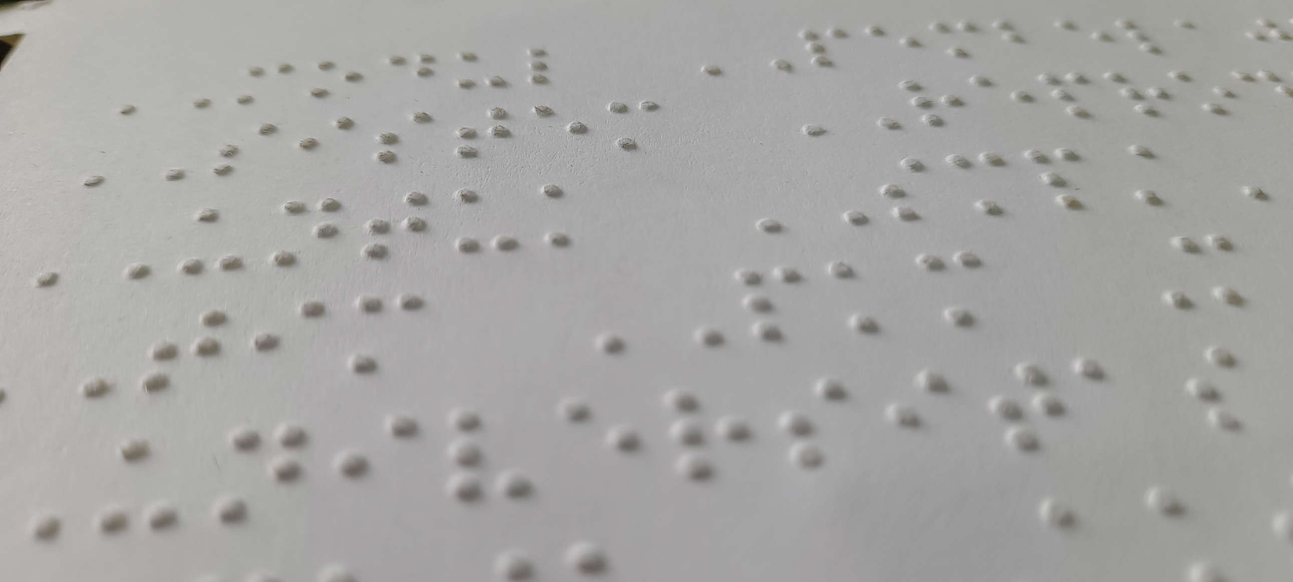 Main Image: A close up image of Unified English Braille (UEB) on white braille paper.