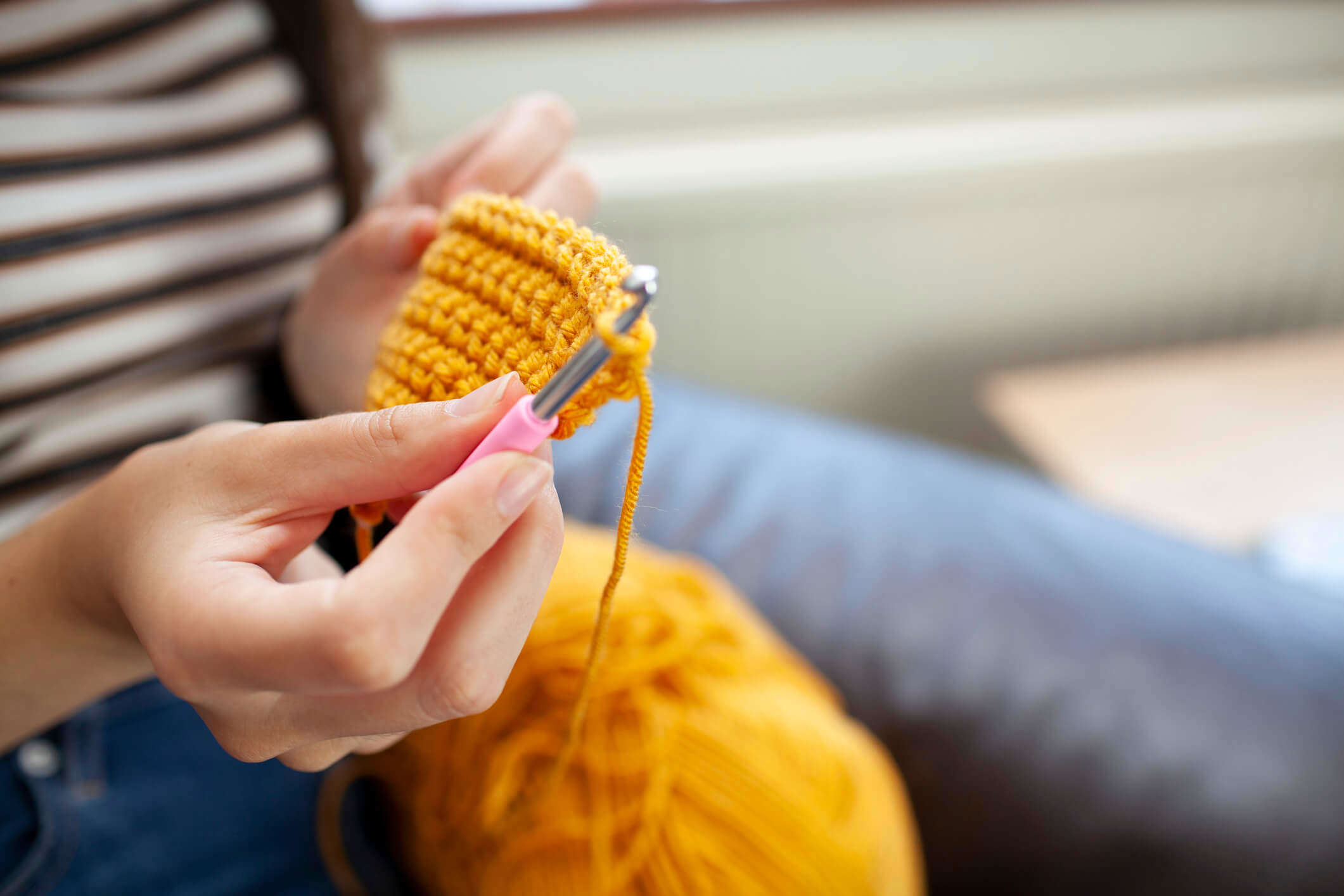 a close up of a crochet hook making a yellow garment