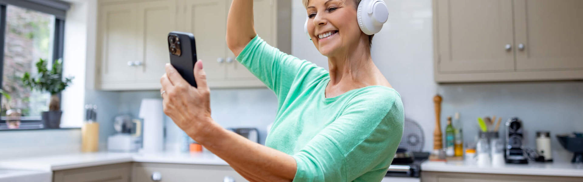 A woman doing a dance class online while listening to headphones