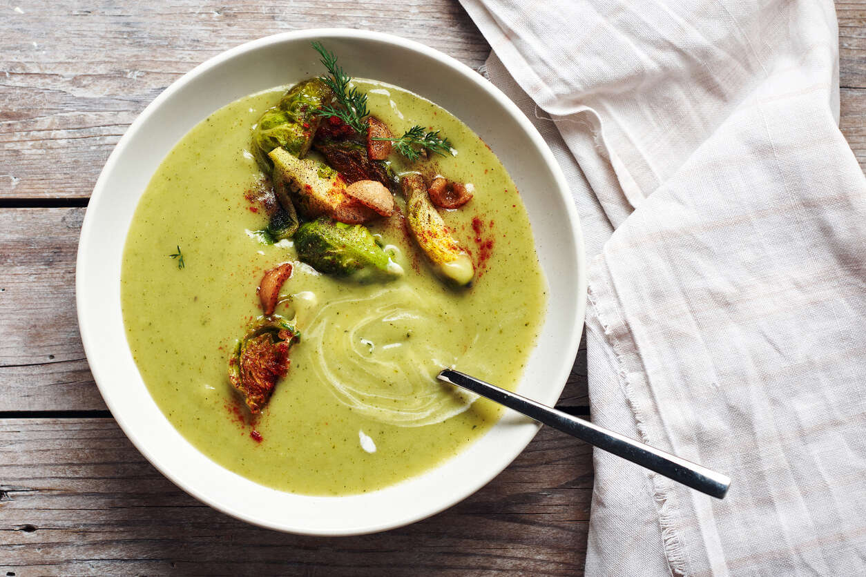 an overhead shot of bright green brussel sprout soup with whole brussel sprouts and paprika