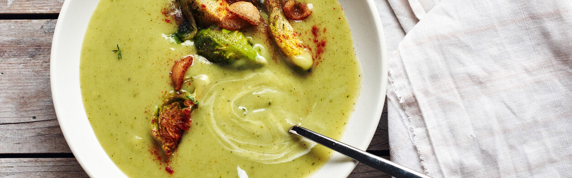 an overhead shot of bright green brussel sprout soup with whole brussel sprouts and paprika