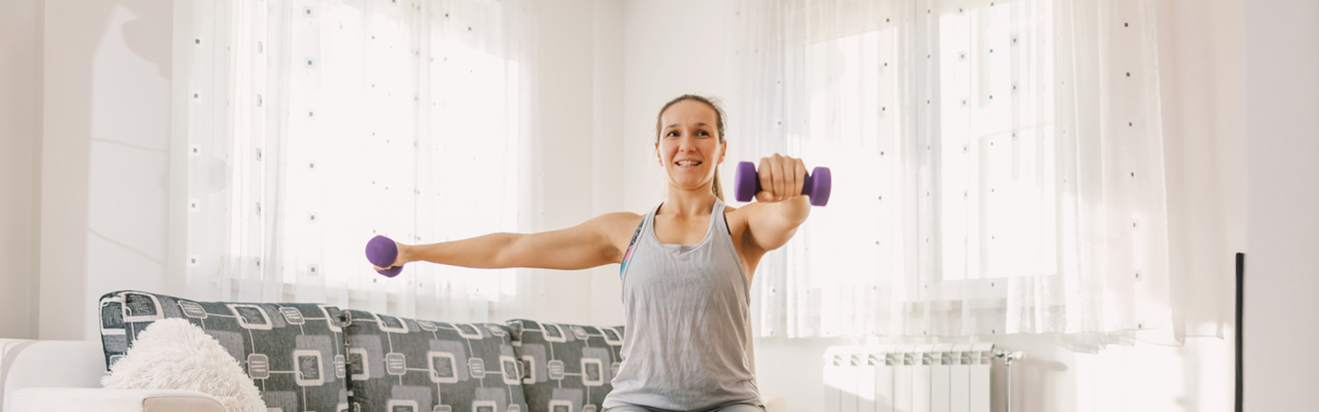 A woman sat on a chair doing exercise with hand weights in the living room
