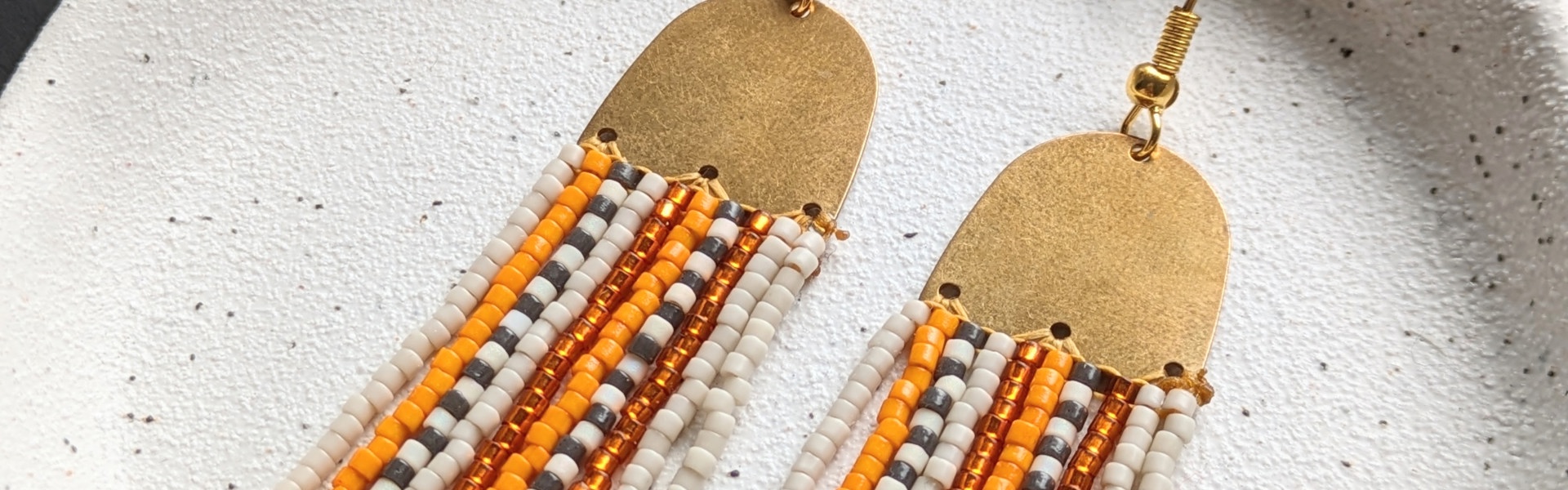 Main image: beaded fringe earrings, in cream, yellow gold, white and black seed beads with  gold metal connector frame. 