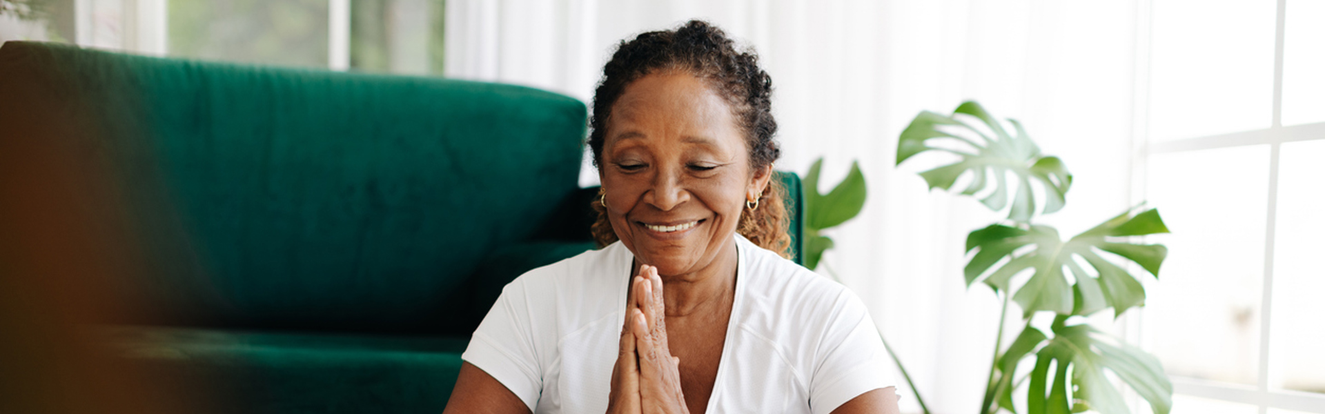 a woman sat cross legged with eyes closed in the living room doing yoga practice at home