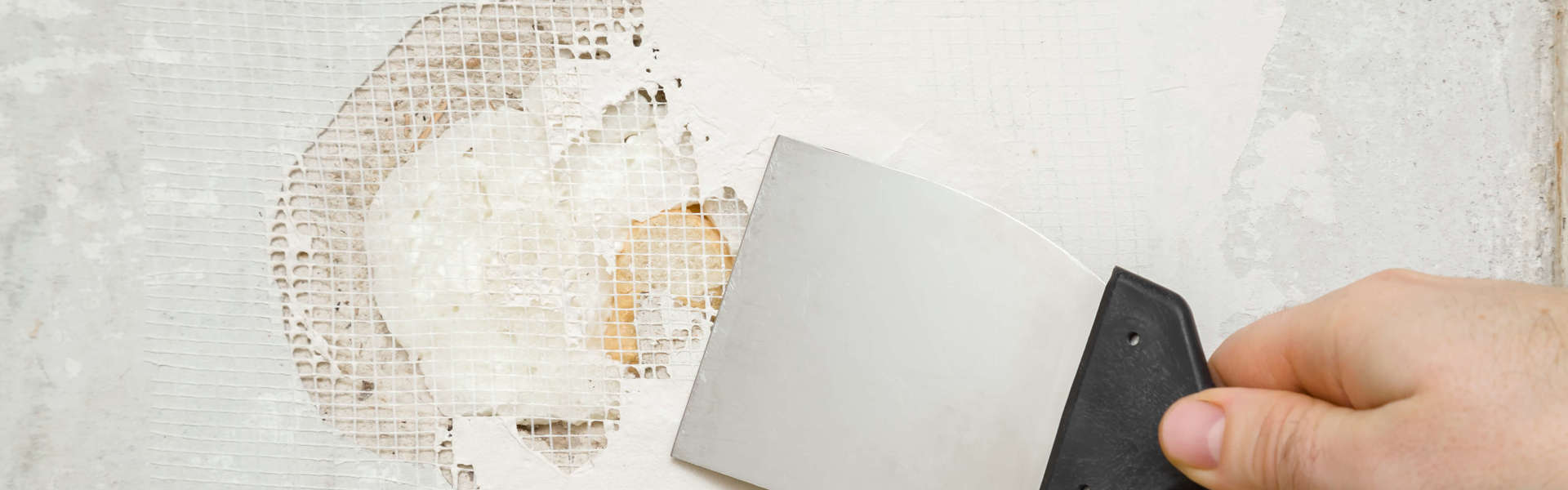 a close up of someone filling in a crack on a white wall