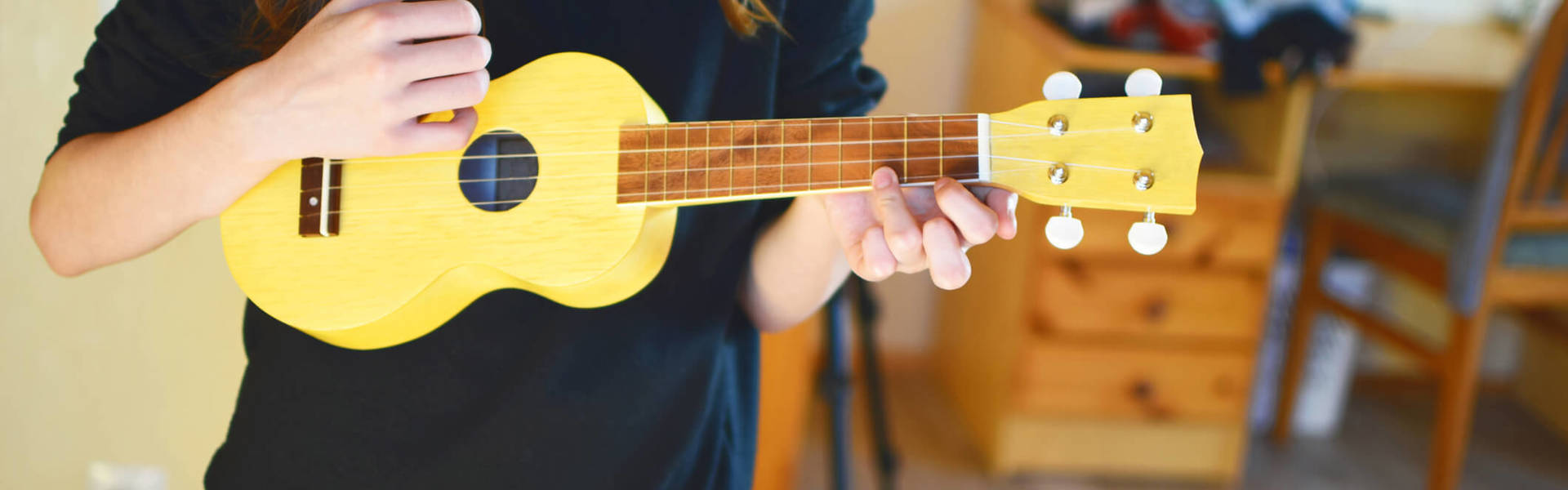 a woman stood up and playing a yellow ukulele