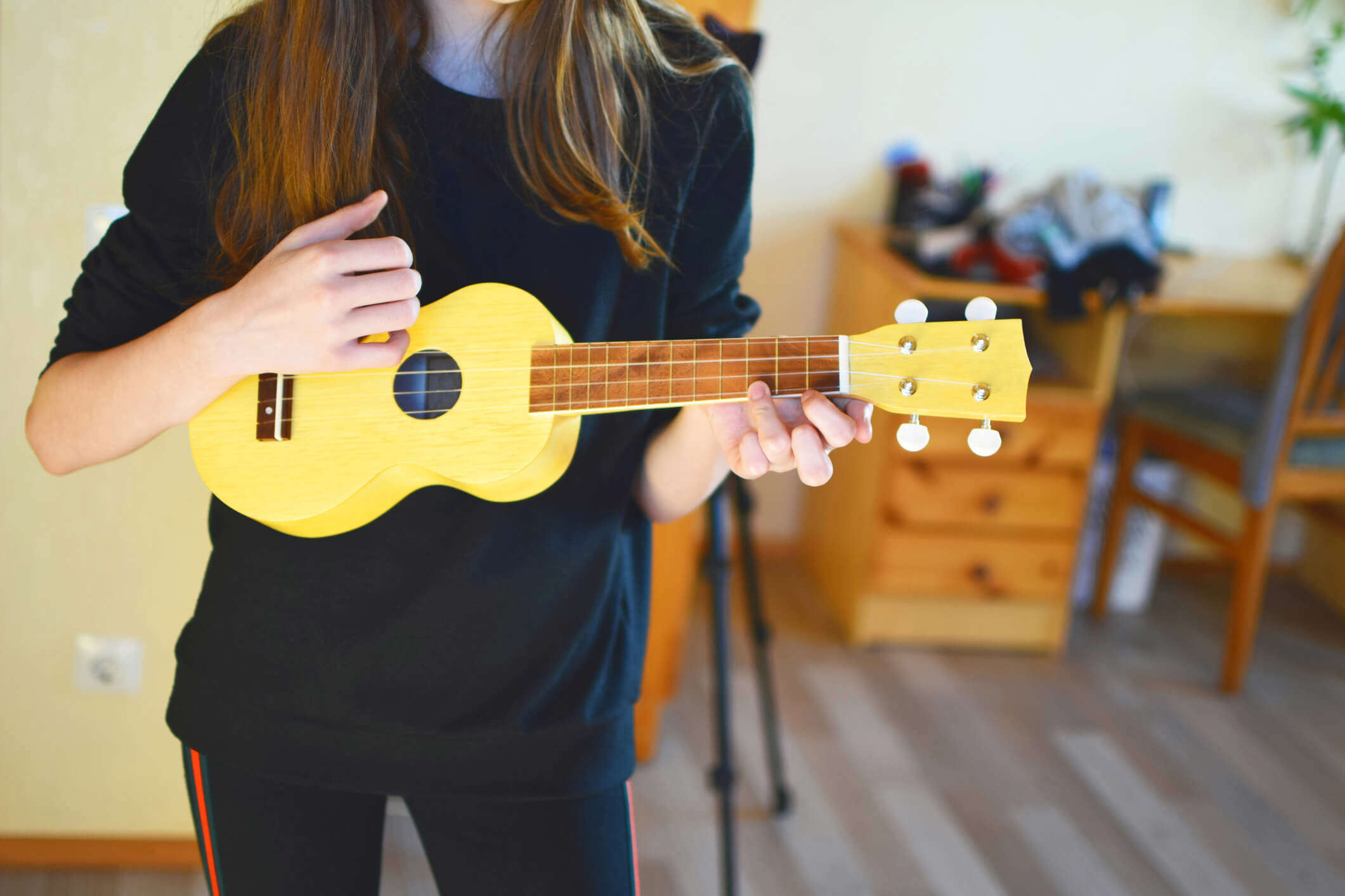 a woman stood up and playing a yellow ukulele