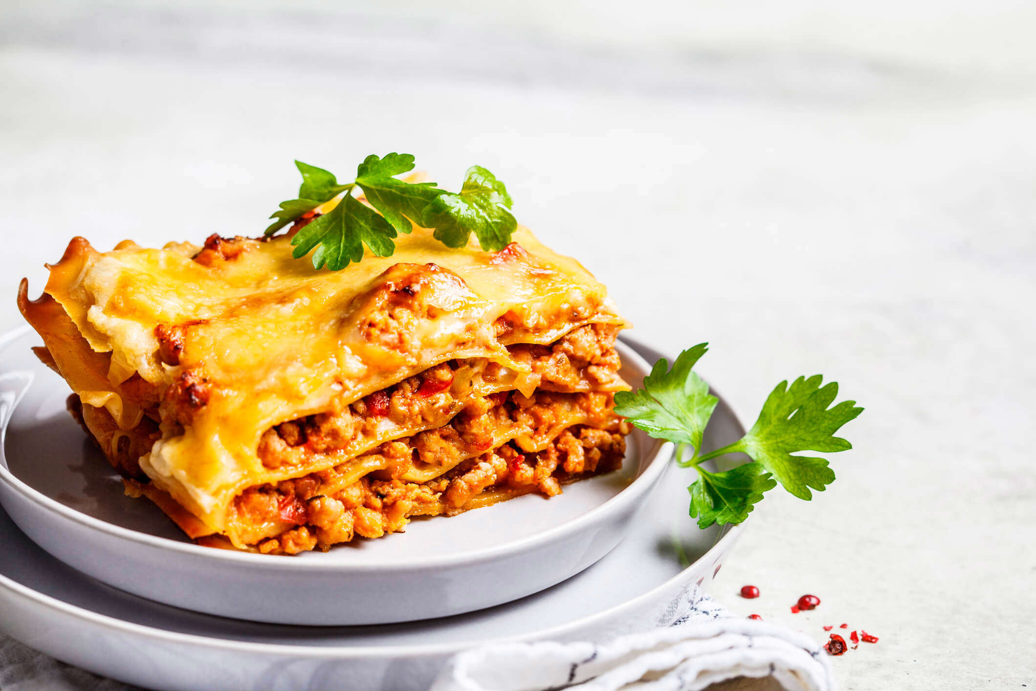 a slice of lasagne topped with green herbs on a white plate