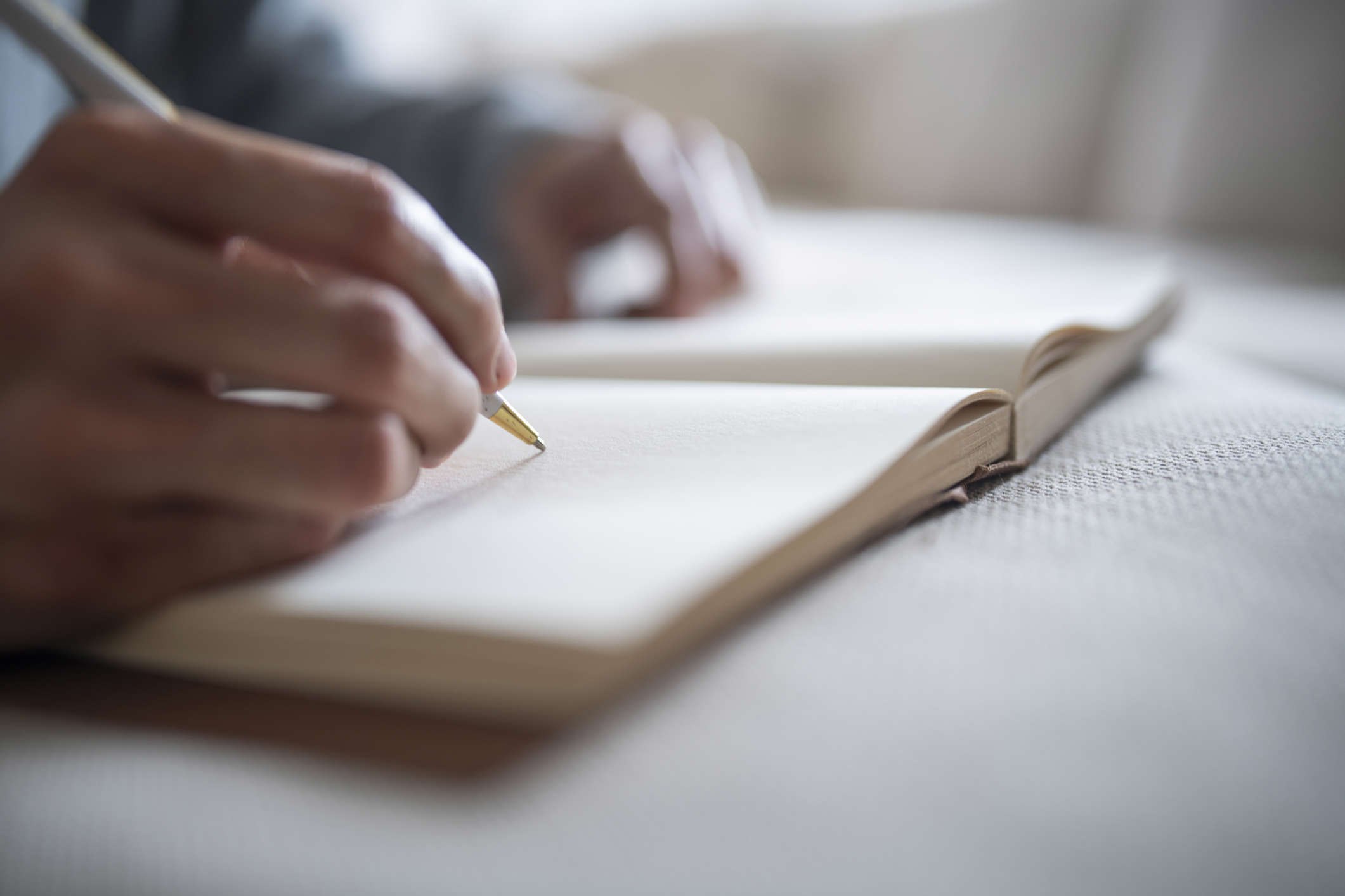 a person writing in an open blank notebook