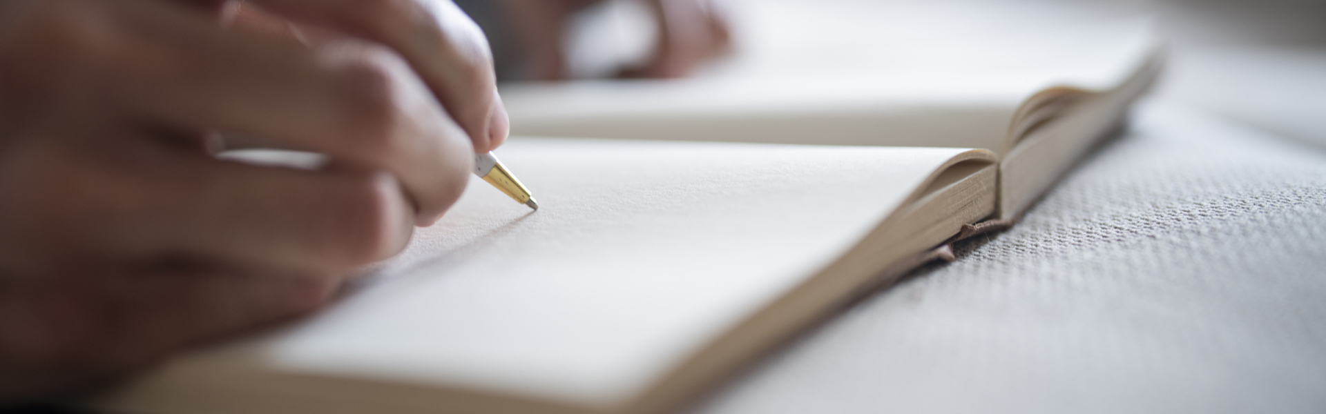 a person writing in an open blank notebook