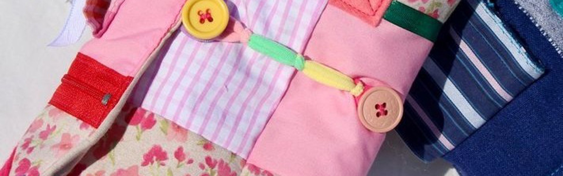 Main image: a handmade twiddle muff, a sensory aid/device, made for a person living with dementia or Alzheimer's. Made with scraps of patterned fabric and various tactile items, like buttons, ribbons, zips. 