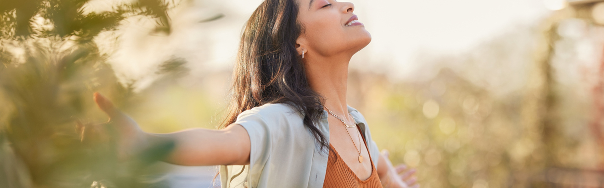 a woman with her arms wide open outside in nature feeling confident