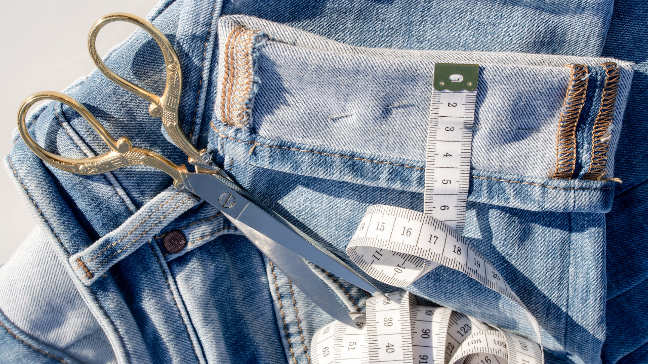 a pair of fabric scissors resting on a pile of denim jeans