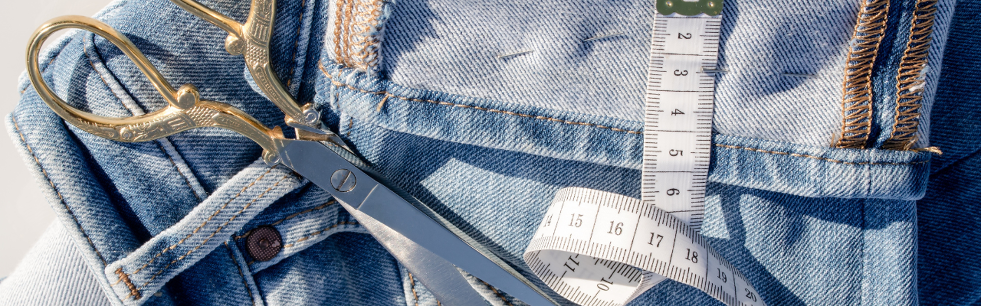 a pair of fabric scissors resting on a pile of denim jeans
