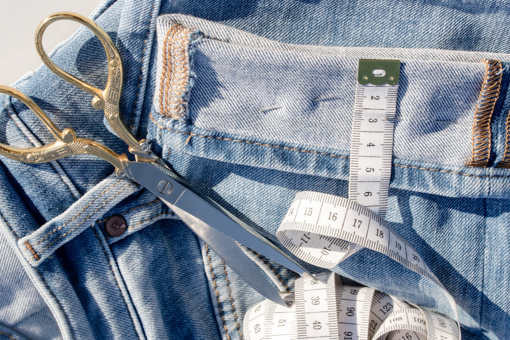 a pair of fabric scissors resting on a pile of denim jeans