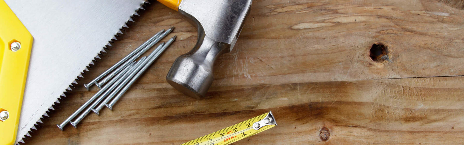 carious DIY tools like a hammer and nails and measuring tape on a wooden background