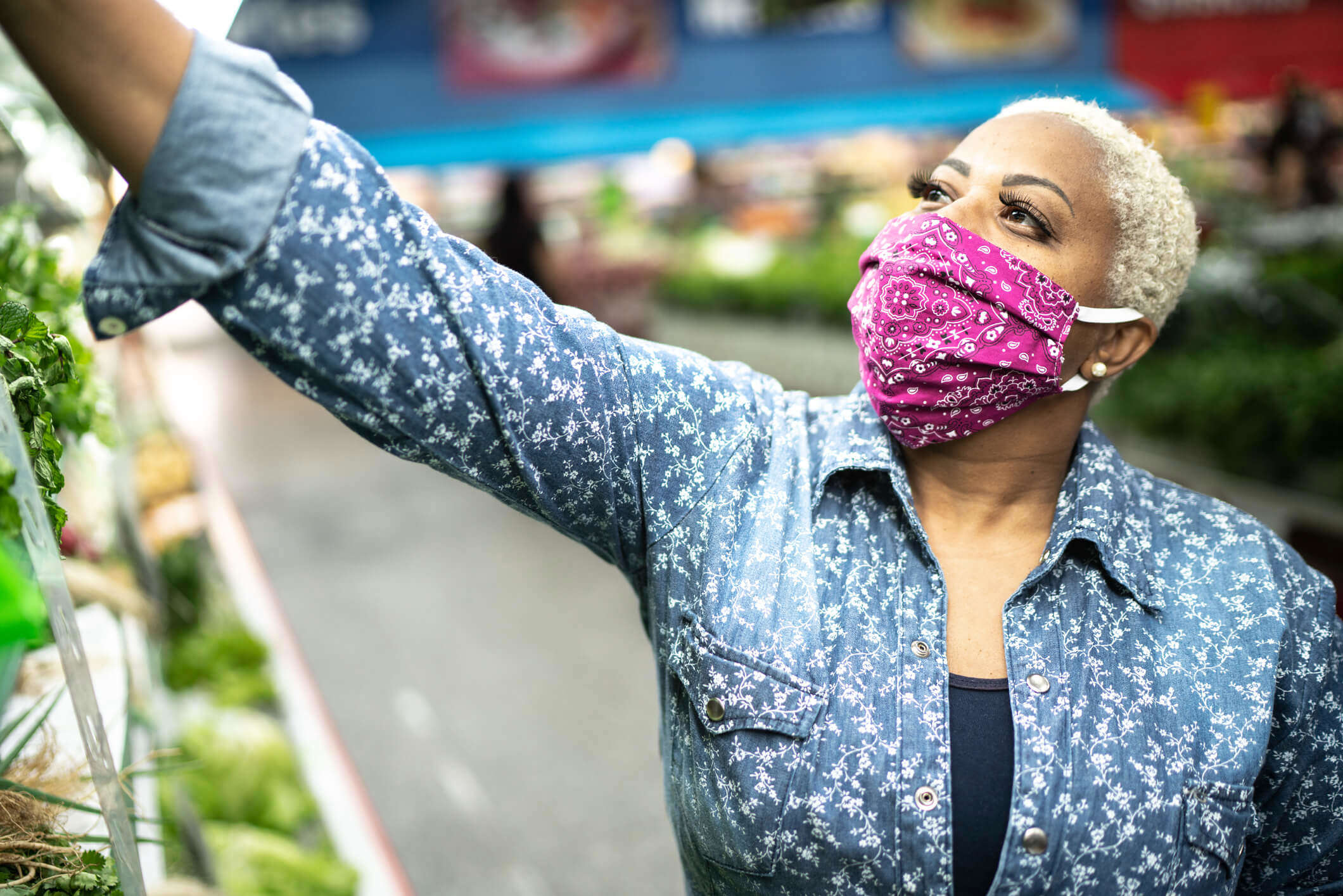 a woman wearing a pink paisley print facemask 