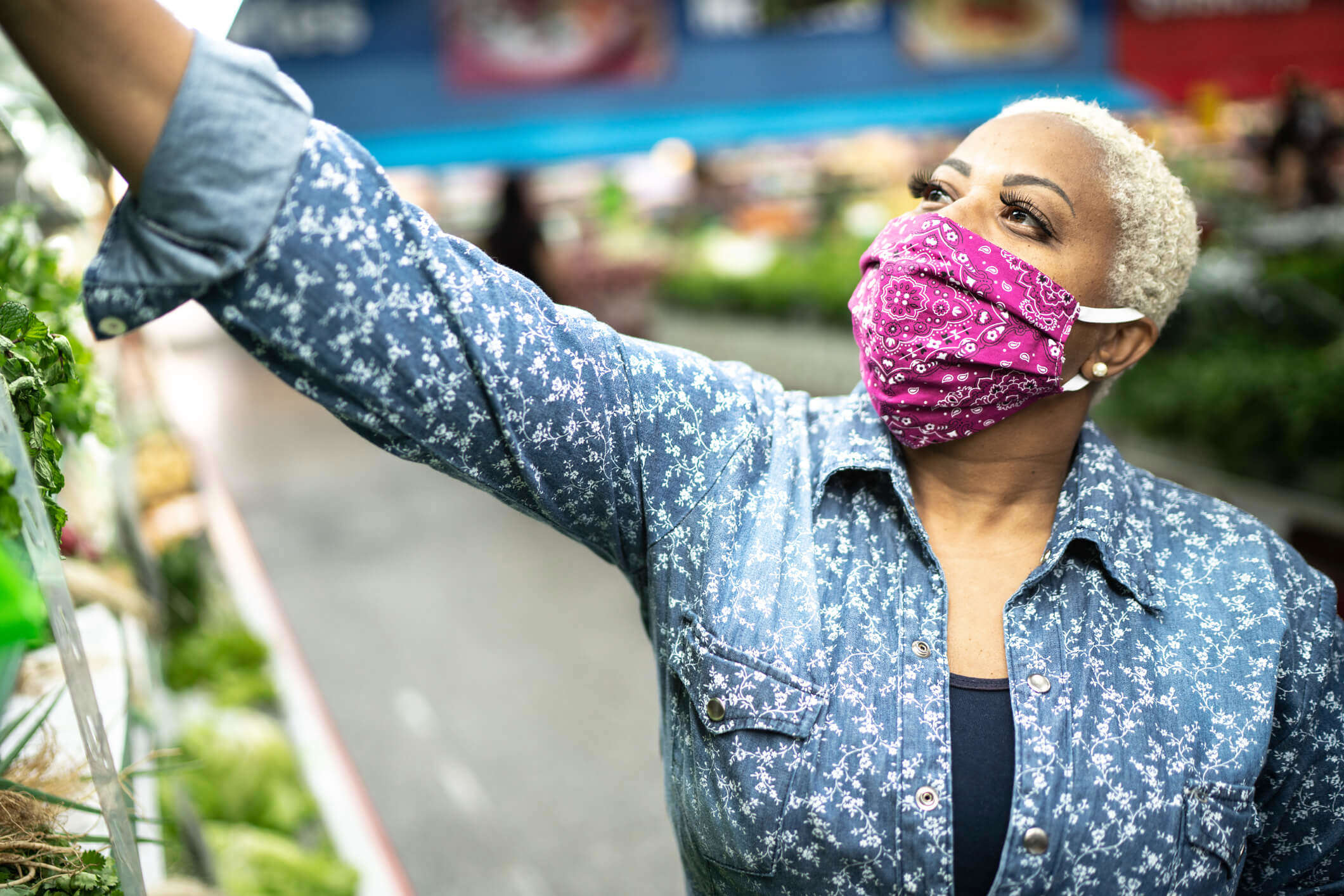 a woman wearing a pink paisley print facemask