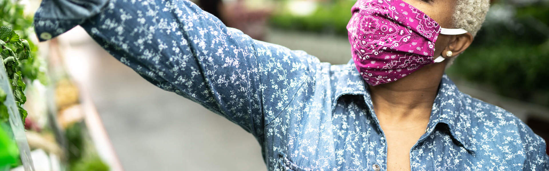 a woman wearing a pink paisley print facemask