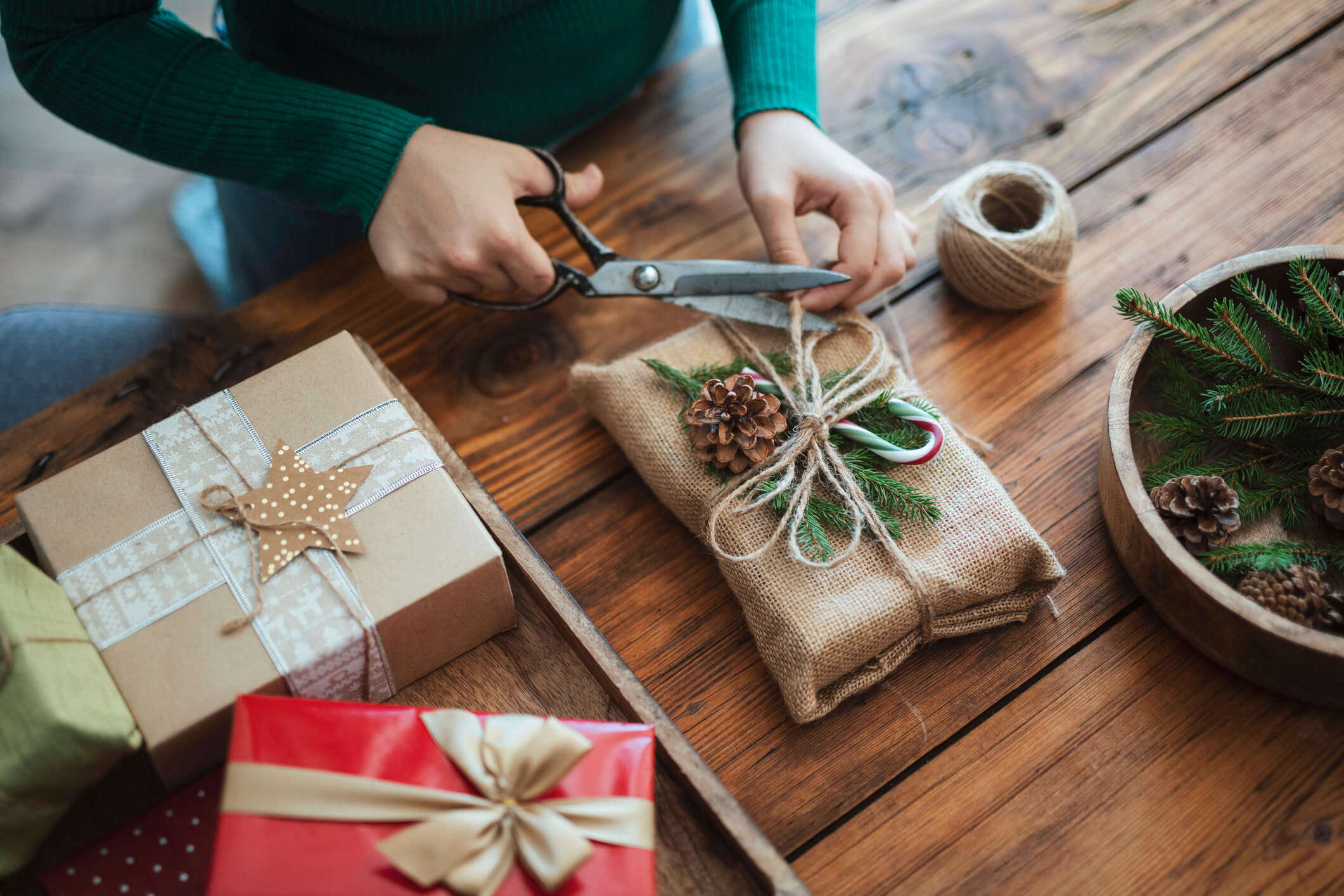 a person wrapping a Christmas gift using eco friendly recycled materials