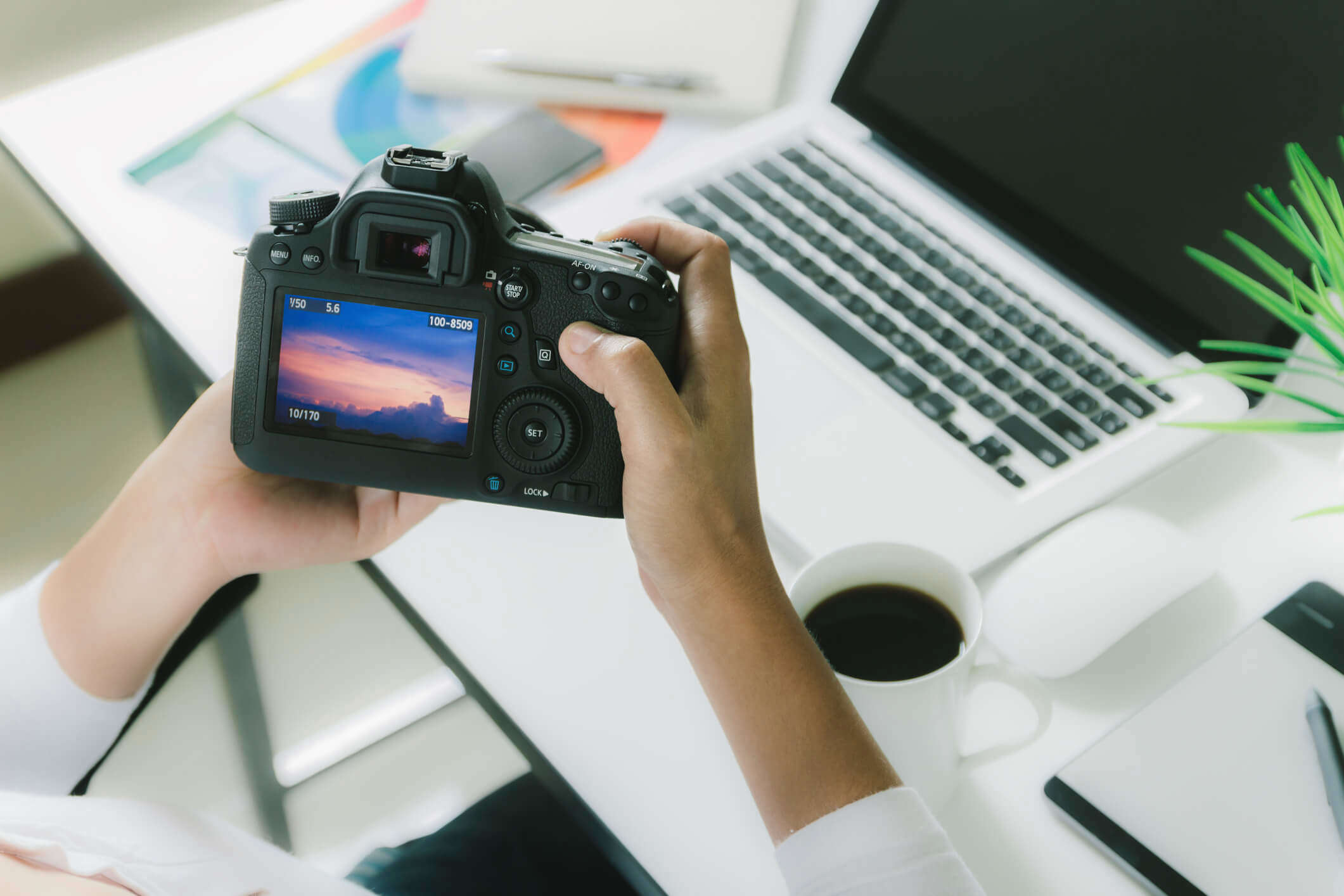 a person sat a work desk looking at a picture on a DSLR camera