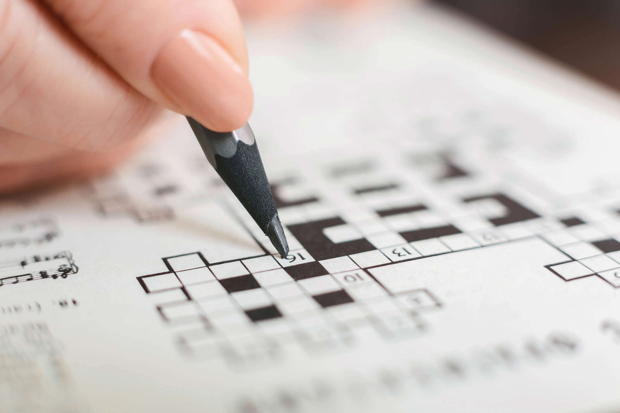 a close up of a person completing a crossword puzzle using a pencil